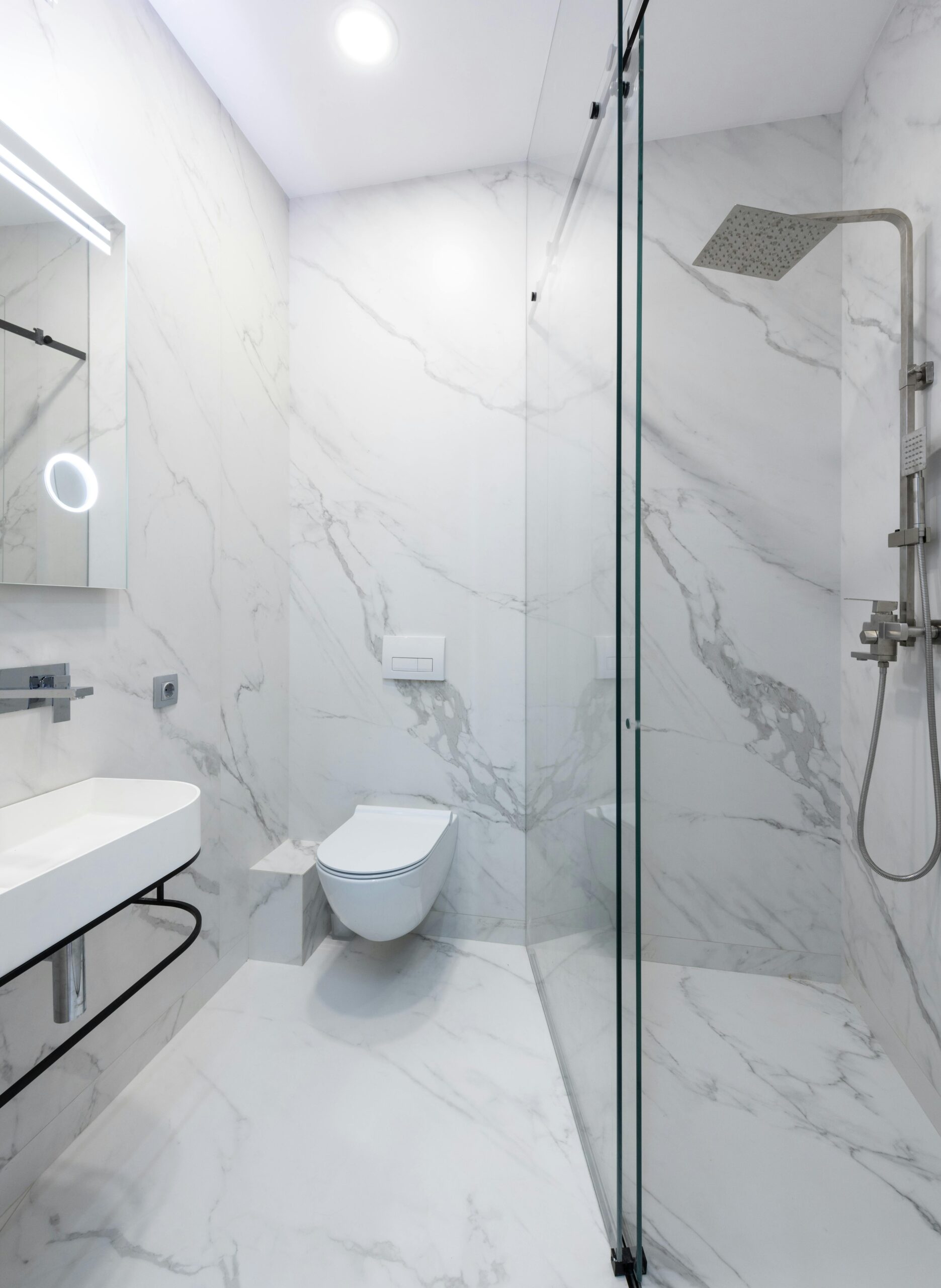Sleek and modern bathroom interior featuring elegant marble walls and a glass shower.